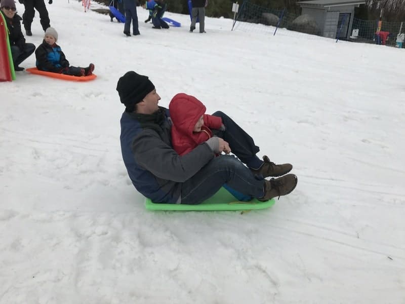 Two Js sitting on a rental toboggan at Lake Mountain. They're a bit cramped for two.